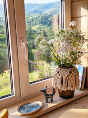 A vase with a bouquet of wildflowers and daisies on a windowsill