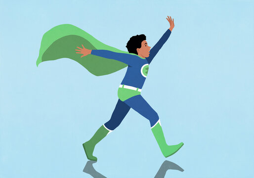 Carefree boy in superhero costume walking with arms outstretched on blue background
