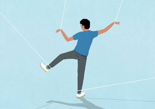 Young man restrained by strings tied to wrists and ankles trying to walk