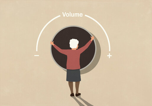 Senior woman adjusting large volume knob against beige background