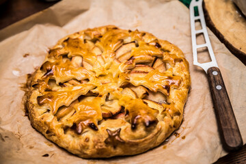 Homemade freshly baked apple pie with star-shaped crust decoration. Rustic fruit tart on baking paper with a knife, cozy dessert at a campsite.