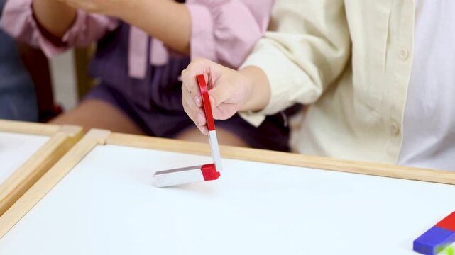 Close Up of Children Learning Physics with Bar Magnets in Classroom