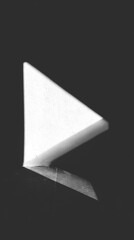 Abstract textured gray triangle shape floating against a stark black background