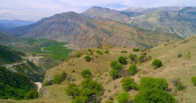 Dagestan mountain valley with river green hills and winding road cinematic aerial forward flight through rugged Caucasus landscape natural environment travel nature scenery