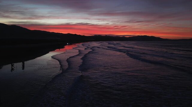 Low-altitude aerial flying along Eztanza Beach showing calm waves, golden light, and tropical shoreline during sunset.