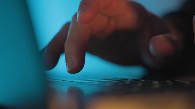Hands typing on laptop keyboard in blue light close-up. Hacking, cybercrime, malware attack, data breach, password cracking, and cybersecurity threat concept. porn addiction. crime
