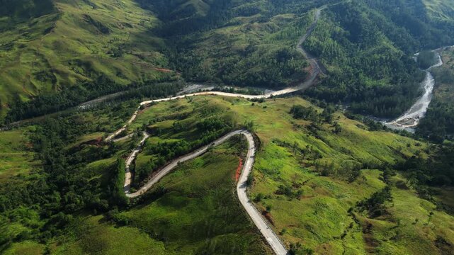 Low-flying drone shot following Daang Katutubo parallel to its curves, showing rolling hills and greenery. Ideal for cinematic storytelling and scenic content.