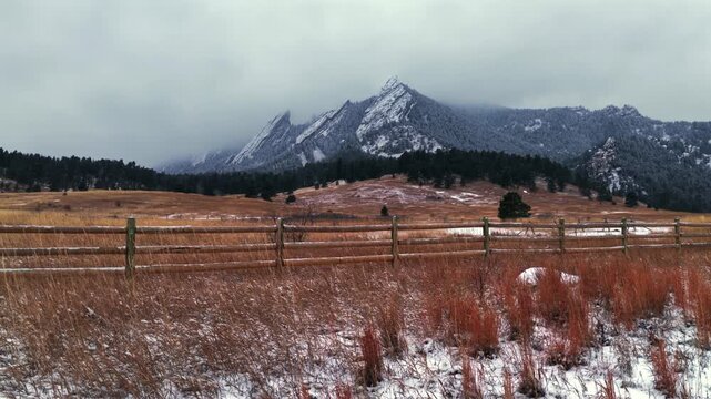 Winter Chautauqua Park Flat Irons Mountain snowing snow flakes snowfall Boulder aerial drone Colorado USA dusk sunset low clouds grass snow covered Rock formation walking loop trail Bear Peak right