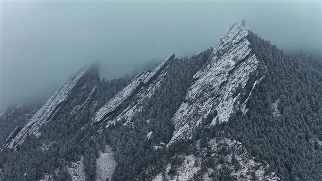 Winter Flat Irons Mountain Chautauqua Park aerial drone Boulder Colorado USA Rock formation snowing snow flakes snowfall dusk sunset low clouds grass snow covered walking loop trail circle right