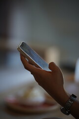 Title: Young woman using a smartphone and holding a cold beverage in a cafe or office.