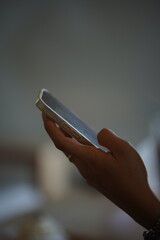 Title: Young woman using a smartphone and holding a cold beverage in a cafe or office.