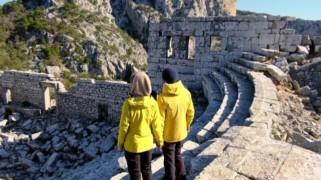 Young travelers discover ancient amphitheater and ruins of Termessos. Walking, climbing, enjoying view and ancient history in warm Turkish light.