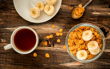 flakes in bowl, tea cup on wooden background top view