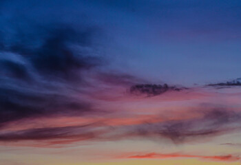 Fototapeta premium Deep purple and blue twilight sky with glowing orange clouds