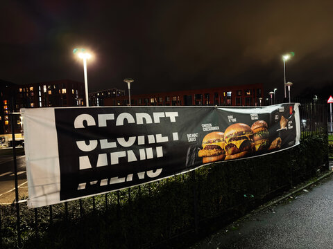 Nighttime McDonalds fast food banner in Manchester shows burgers, street lights, and urban colors