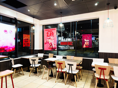 Modern KFC cafe interior in Manchester with bright posters, wooden tables, and seating for groups