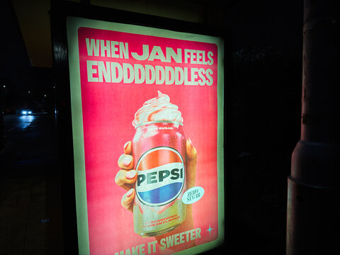 Pepsi can with whipped strawberries cream in a bold pink advertisement at night in Manchester UK