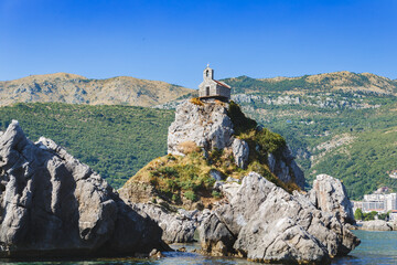 Fototapeta premium Small Stone Chapel on Rocky Islet near Podgorica, Montenegro, Surrounded by Mountains and Blue Sea