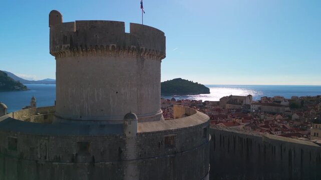 Aerial reveal of Dubrovnik Old Town with rising drone and camera tilt down. Historic Minceta Tower and red roofs panorama. 4K.
