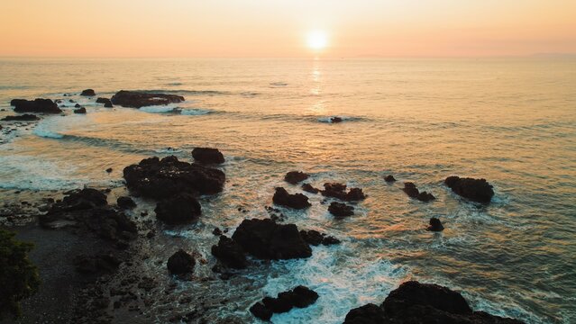 Rocky coastline of Jaco beach illuminated by warm golden sunset light Costa Rica.
