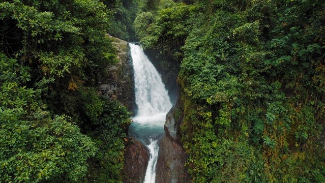 Powerful waterfall pouring into canyon surrounded by dense tropical rainforest.