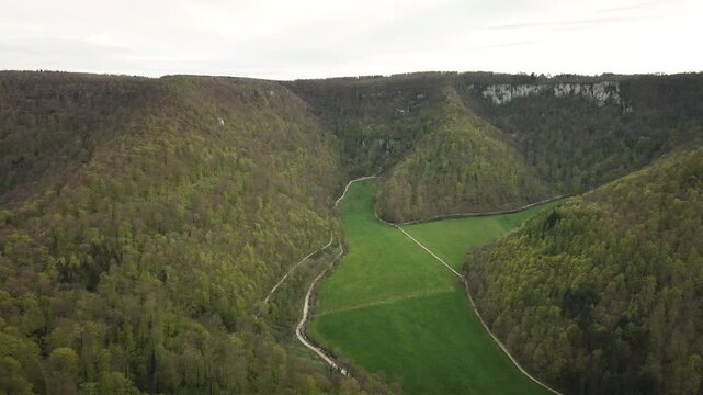 Smooth 4K UHD drone push-in flying forward into the Gro&szlig;e Lautertal (Lauter Valley) in the Swabian Alb, showcasing forested hills and vivid green meadows&mdash;ideal for travel films, ads.