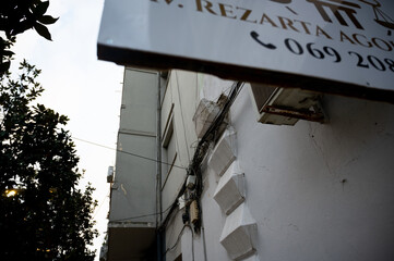 Detached facade decoration hanging on overhead wires above pedestrians.