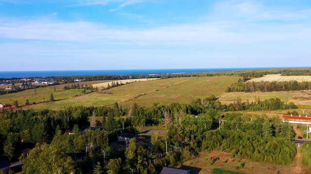 Aerial drone footage showing a landscape view over framers fields and the ocean in the background located on Prince Edward Island in Nova Scotia Canada on a bright sunny autumn day