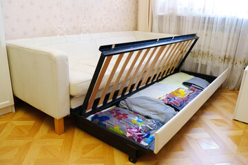Storage space under the sofa for blankets and clothes in a living room
