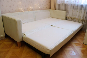 Sofa is opened to reveal space for sleeping in room with curtains