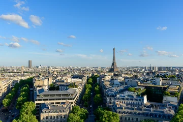 Fotobehang Eiffeltoren Expansive panoramic view over Paris featuring the Eiffel Tower rising above classic city rooftops and tree-lined avenues under a bright blue sky with scattered clouds.  © Florent