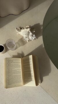 Minimal still life with open book and seashell decor on natural stone surface. Tropical slow living composition inspired by Bali interiors.
