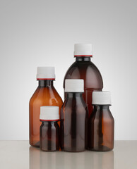 Various sizes of blank Brown medicine bottles with white caps on a table for branding