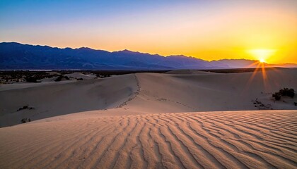 Sunrise over desert dunes and distant mountains