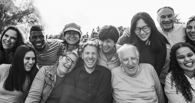 Group of multigenerational people smiling in front of camera - Multiracial friends with different ages having fun together - Main focus on center faces - Black and white