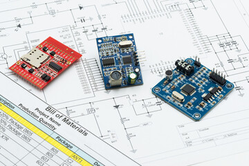 Close-up of development circuit boards placed on a schematic and bill of materials, representing embedded systems design, electronics prototyping, IoT engineering, and hardware innovation workflow.