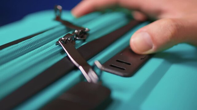 Secure suitcase with combo lock, Hands set combination on teal suitcase with textured surface, Closeup of hands adjusting numeric lock on stylish teal travel suitcase