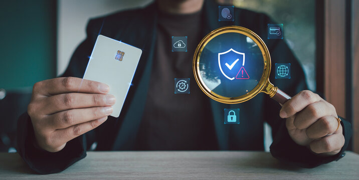Businessman hand holding credit card and magnifying glass detecting virtual fraud warning sign on security shield for financial risk management concept, Security Analysis Investigation, Verified Safe