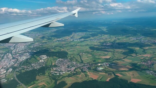 Passenger Plane Wing in Blue Sky Above Clouds, Scenic Landscape Below