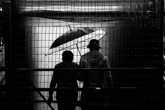 Pessoas usando capa de chuva e guarda chuva. 