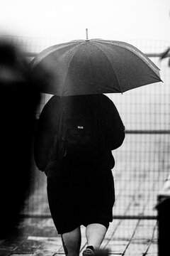 Pessoas usando capa de chuva e guarda chuva. 