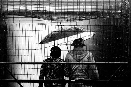 Pessoas usando capa de chuva e guarda chuva. 