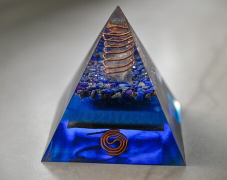 High resolution color image of a Blue Orgone Pyramid Crystal, Handmade Energy Healing Object on White Marble Background, Spiritual Protection and Cleansing Tool