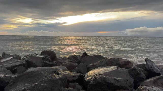 Ocean waves crashing on black rocks at sunset under storm clouds coastal seascape