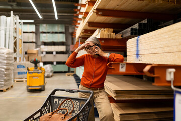 Woman in orange sweater talks on phone while sitting on cart in a lumber store during the day
