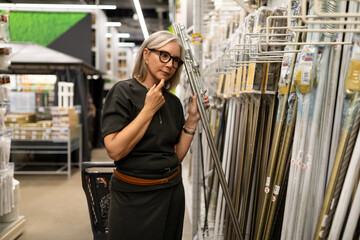 Woman shopping for home improvement supplies in a hardware store while contemplating her options for a new project