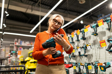 Woman shopping for tools in a hardware store while talking on the phone during a busy afternoon