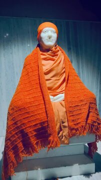 Shirdi Sai Baba draped in saffron shawl, symbolizing spirituality, faith, and devotion, displayed in a serene temple setting for worship and meditation.