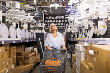 Woman shopping for lights in a home improvement store during daylight hours