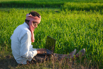 Indian rural man using laptop at agriculture field. Modern technology in agriculture